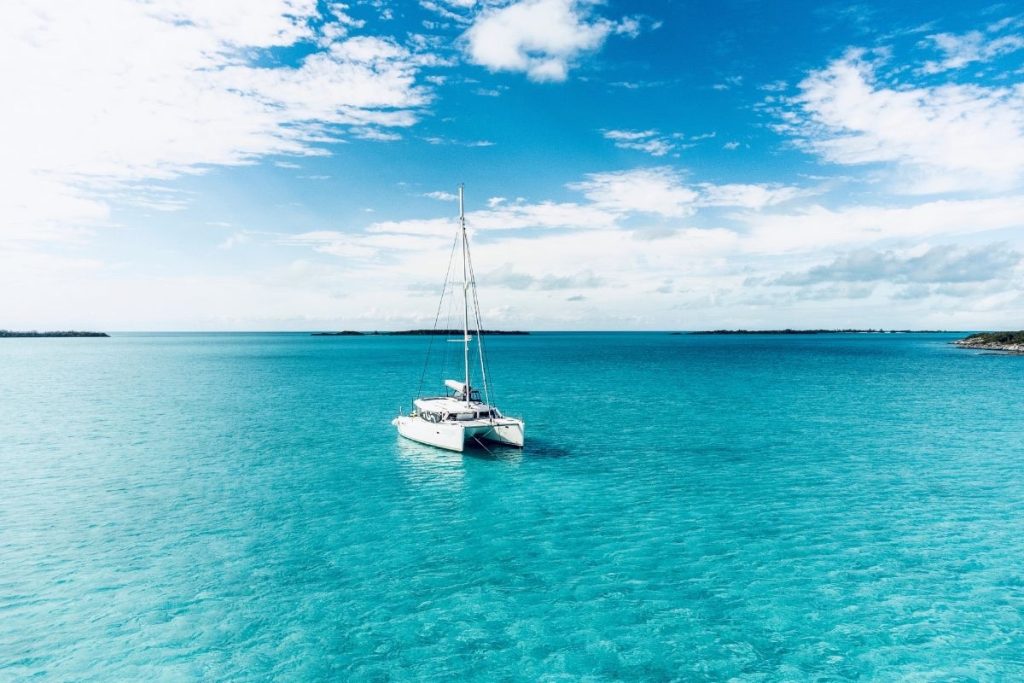 White catamaran anchored in the turquoise waters of the Exumas, Bahamas under a bright blue sky, showcasing luxury catamaran charter experience.